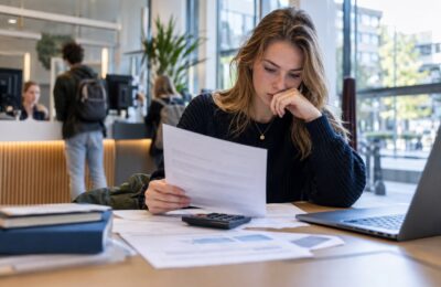 Studente bekijkt documenten over haar studielening met een rekenmachine